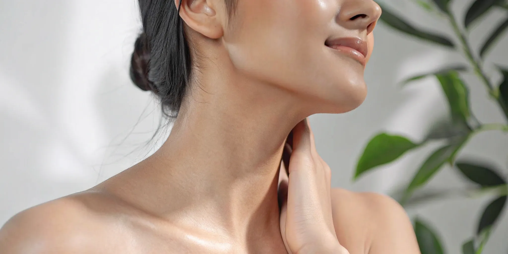 Woman touching her smooth neck and firm jawline, a result of neck tightening.