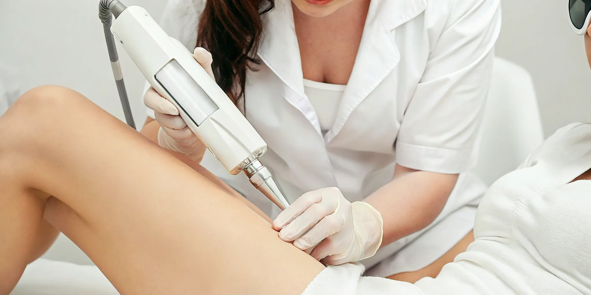 Technician using a laser for a small tattoo removal session on a leg.