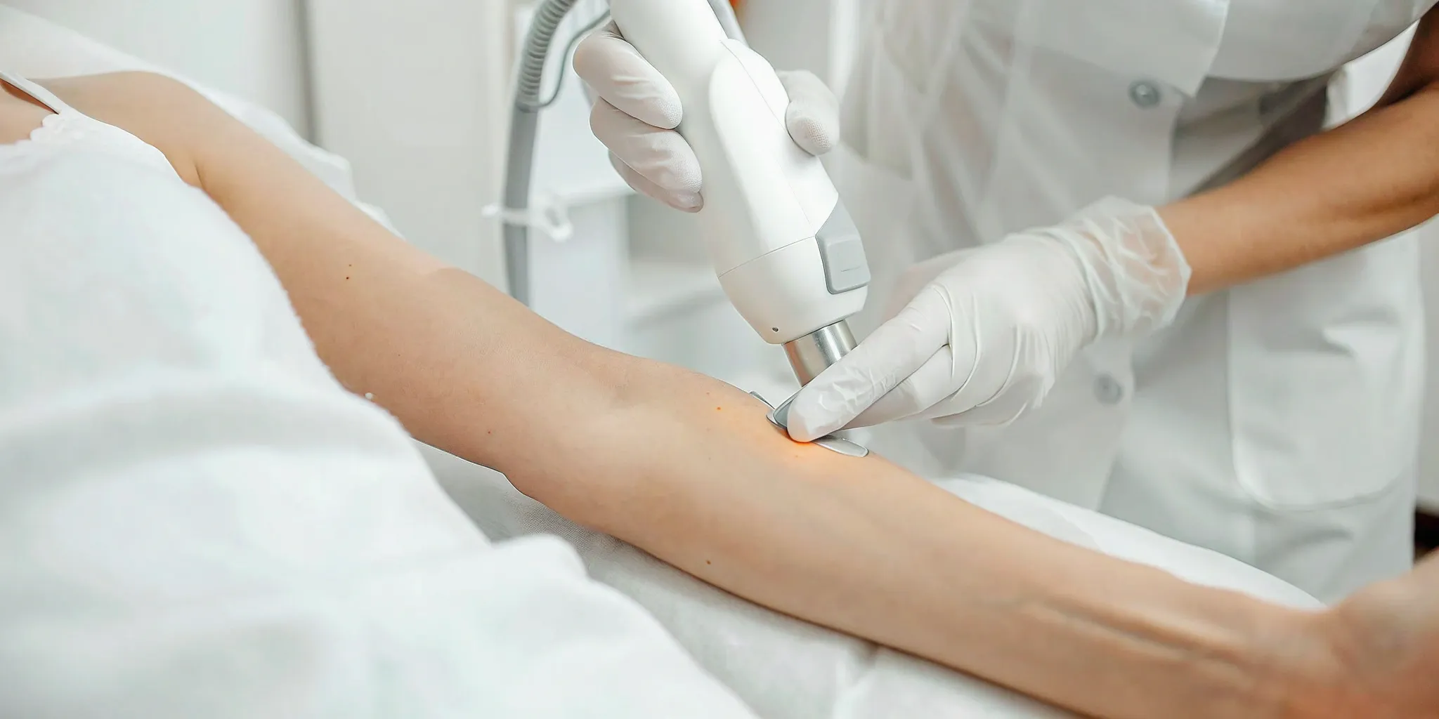 A specialist performing advanced laser tattoo removal on a client's forearm.