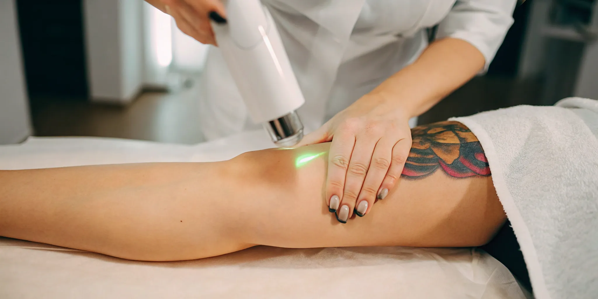 Laser targeting a colorful tattoo on a leg during a color tattoo removal treatment.