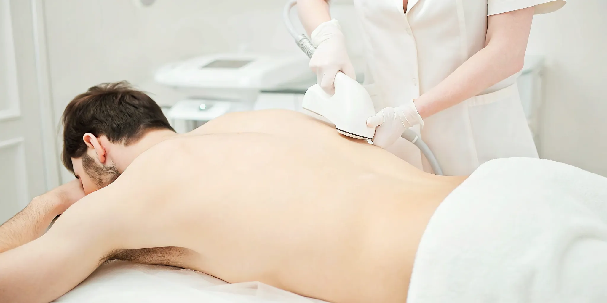 Men's laser hair removal treatment on back in a medical spa treatment room