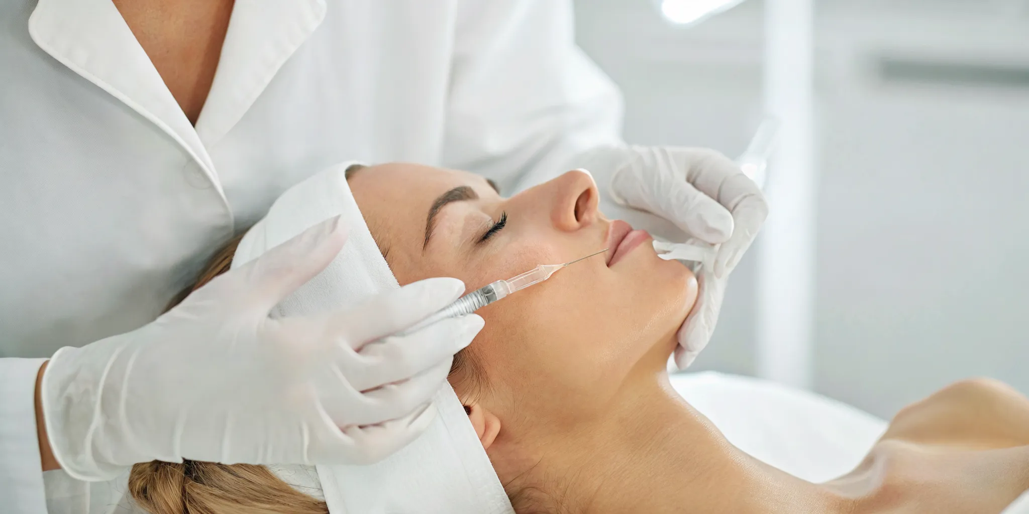 Medical aesthetician gently performing a dermal filler treatment on a relaxed woman in a modern Dallas med spa
