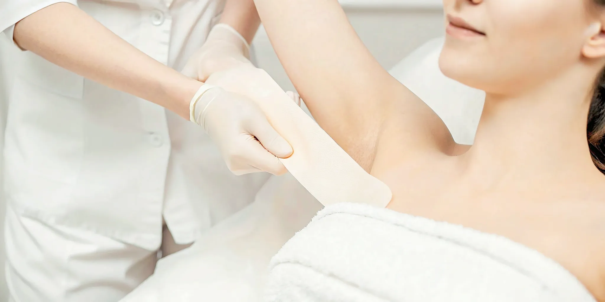 Woman applying a cool compress to her arm after laser hair removal treatment in a medical spa